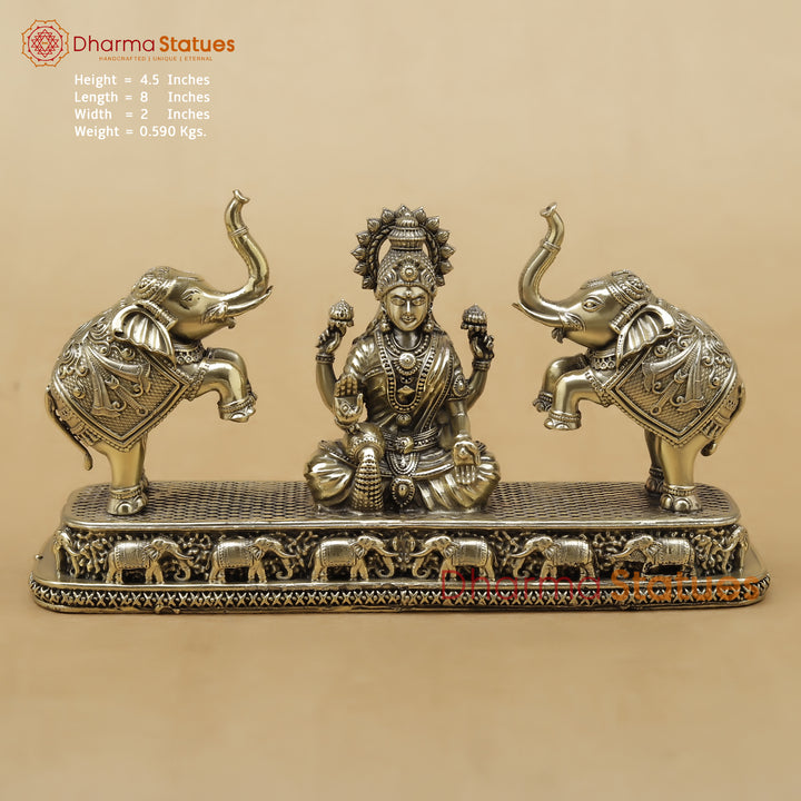 Decorative statue of a seated figure with two elephants on a beige background, featuring Dharma Statues branding.